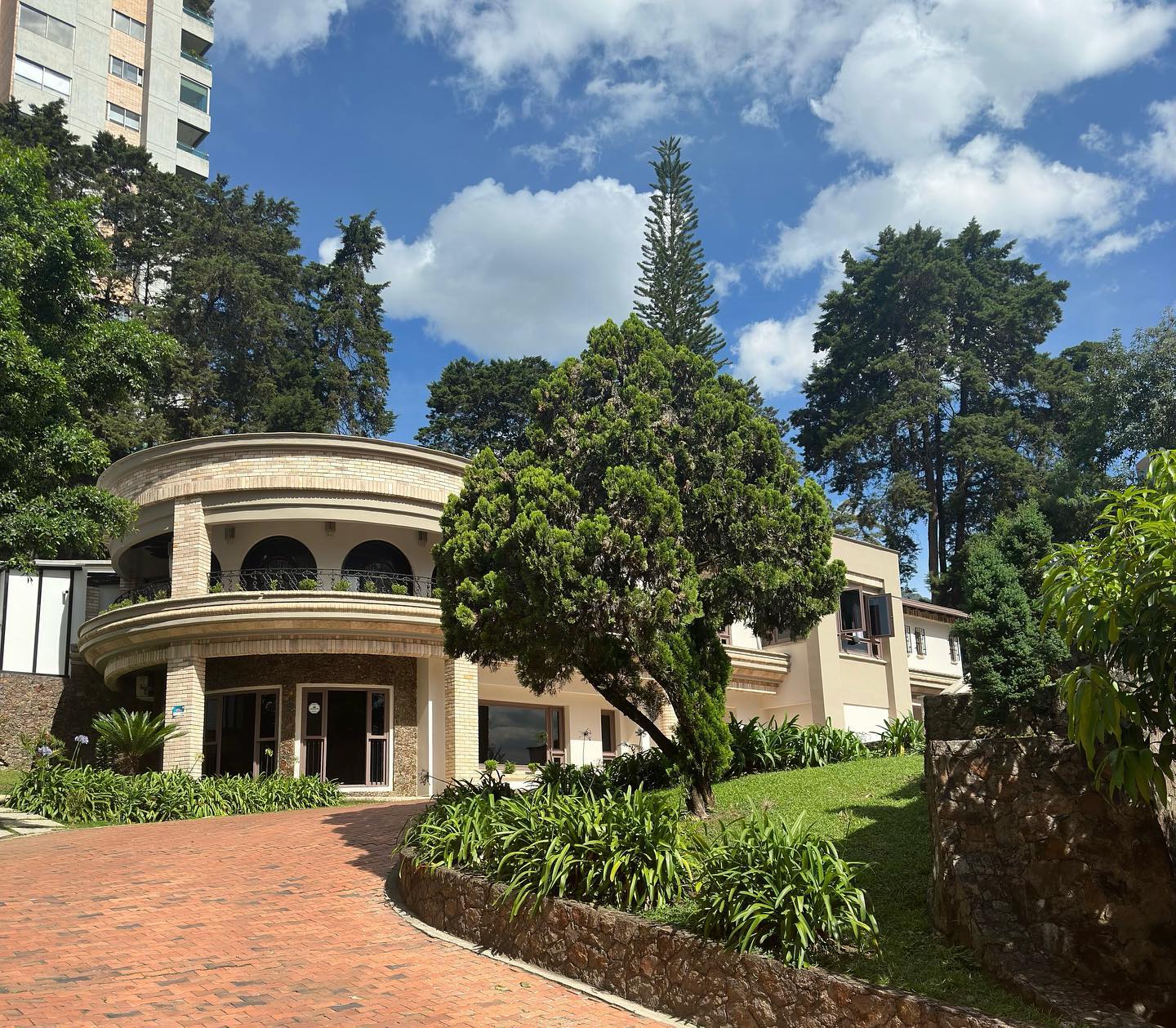 A rounded brick mansion among tall pines in Medellín