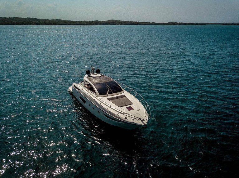 A white yacht at anchor on dark blue water near an island
